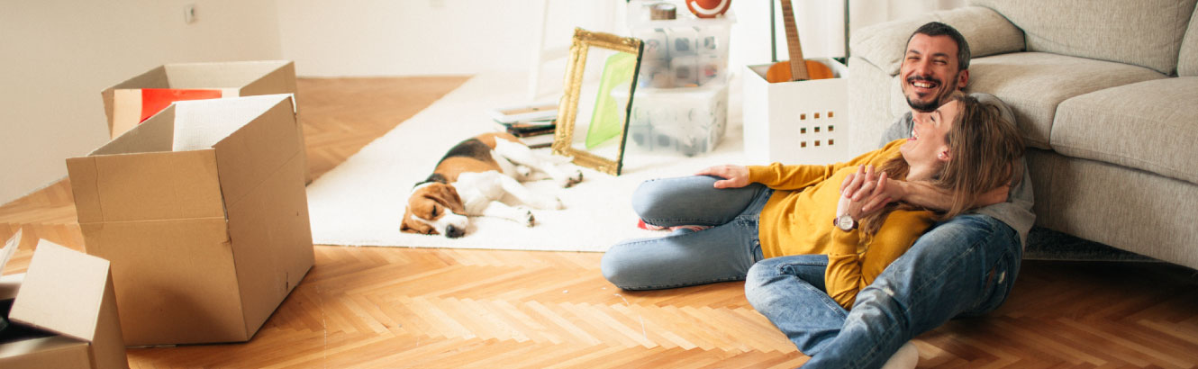 A young couple and their dog relaxing after moving into a new home.